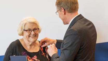Daniel Günther steckt Hildegard Welbers das Bundesverdienstkreuz an