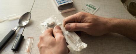 Safer Use Zwei Hände öffnen die Verpackung einer steril eingepackten Spritze für Safer Use